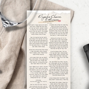 Puede incluir: Un mantel de lino blanco y beige con una copa de vino y una botella de vino. Una hoja de papel impresa con texto hebreo está sobre el mantel. El texto dice "Eliyahu Chaim & Miriam A Perfect Match".