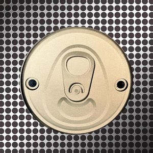 Pu&ograve; includere: Primo piano di un coperchio di lattina dorato con linguetta e due piccoli rivetti neri. Il coperchio &egrave; centrato su una superficie metallica grigia con un motivo di piccoli punti neri distanziati.