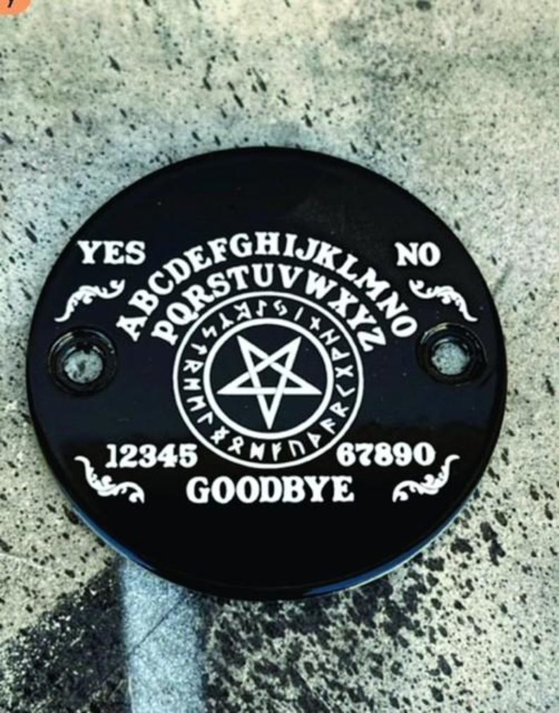 Pu&ograve; includere: Una planchette Ouija nera e circolare con lettere e simboli bianchi. La planchette presenta l'alfabeto, i numeri e le parole "YES", "NO" e "GOODBYE". Una stella a cinque punte &egrave; al centro.