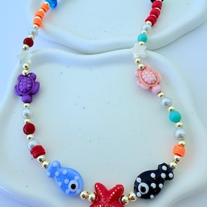 セラミックチャーム、淡水真珠、金メッキのベース、海洋生物のフィギュアが付いた手作りのビーチデイネックレス。
