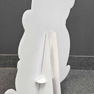 Peut inclure: D&eacute;coupe en carton blanc en forme d'ours, vue de dos. La d&eacute;coupe est soutenue par un support &agrave; l'arri&egrave;re, lui permettant de tenir debout. La forme d'ours a des bords arrondis et un design simple.