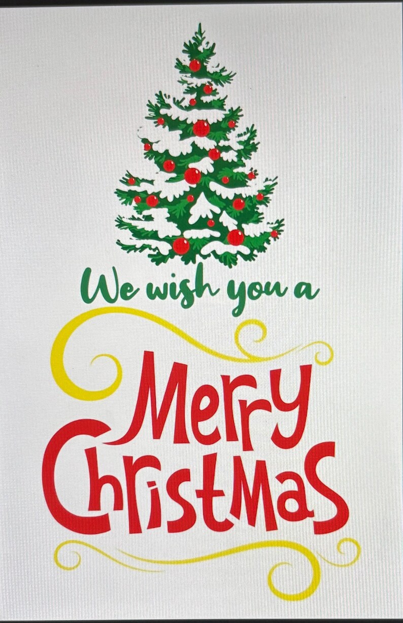 K&ouml;nnte beinhalten: Weihnachtsgrafik mit einem gr&uuml;nen Weihnachtsbaum, der mit roten Kugeln und wei&szlig;em Schnee geschm&uuml;ckt ist. Der Text "We wish you a Merry Christmas" ist in Gr&uuml;n, Gelb und Rot geschrieben.