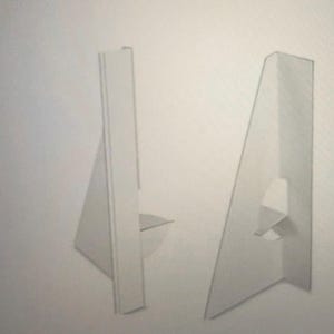 Op de afbeelding: Twee witte kartonnen display stands. Elke stand heeft een driehoekige basis en een verticale steun met een sleuf. De stands zijn ontworpen om items rechtop te houden voor weergave.