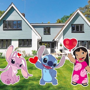 May include: Outdoor yard decorations featuring characters from the animated film Lilo & Stitch. The set includes a pink Angel character, a blue Stitch character, and Lilo holding a red heart balloon. The characters are set on a green lawn in front of a house.