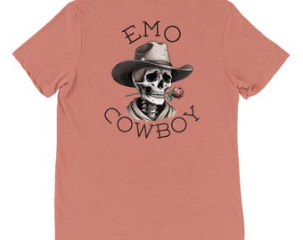 May include: A coral pink t-shirt with a graphic of a skeleton wearing a cowboy hat and holding a rose. The text "EMO COWBOY" is printed below the graphic.