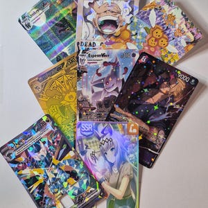 May include: A collection of holographic trading cards featuring various characters and designs. The cards display vibrant colors, including gold, purple, and blue, with text such as "WANTED" and character names. Some cards have a "310" or "320" value.
