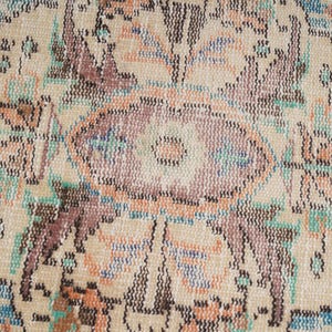 Pode incluir: Close-up de um tapete bege com um padr&atilde;o floral em tons de marrom, azul e rosa. O tapete tem uma textura tecida e um design detalhado.