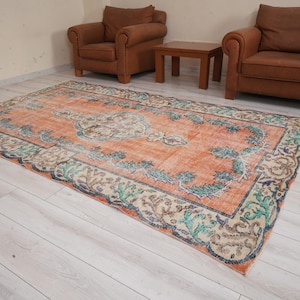 Pode incluir: Um tapete vintage com um padr&atilde;o floral em tons de laranja, verde e bege. O tapete tem um visual desgastado e &eacute; perfeito para adicionar um toque de estilo bo&eacute;mio a qualquer c&ocirc;modo.