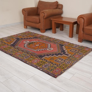 Pode incluir: Um tapete vintage colorido com um padrão geométrico em tons de vermelho, laranja, amarelo, azul e verde. O tapete tem um visual desgastado e é perfeito para adicionar um toque de estilo boêmio a qualquer cômodo.