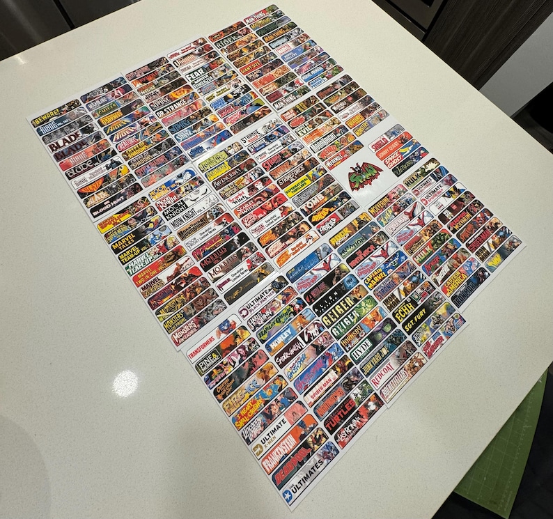 Peut inclure: Une collection d'autocollants rectangulaires color&eacute;s avec divers noms et logos de personnages de bandes dessin&eacute;es. Les autocollants sont dispos&eacute;s en rang&eacute;es sur une surface blanche. Certains des noms incluent "Blade", "Fear", "Marvel", "Ultimate", "Frankenstein", "Ultimates", "Horley", "Lien", "Geiger", "Hulk", "Hyde", "Echh", "SGT FURY", "Turtles", "Redcoat".