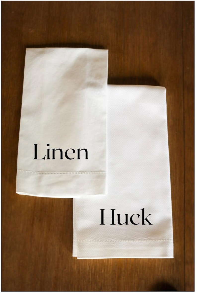 K&ouml;nnte beinhalten: Zwei wei&szlig;e K&uuml;chent&uuml;cher, eines mit der Aufschrift "Leinen" und das andere mit der Aufschrift "Huck".