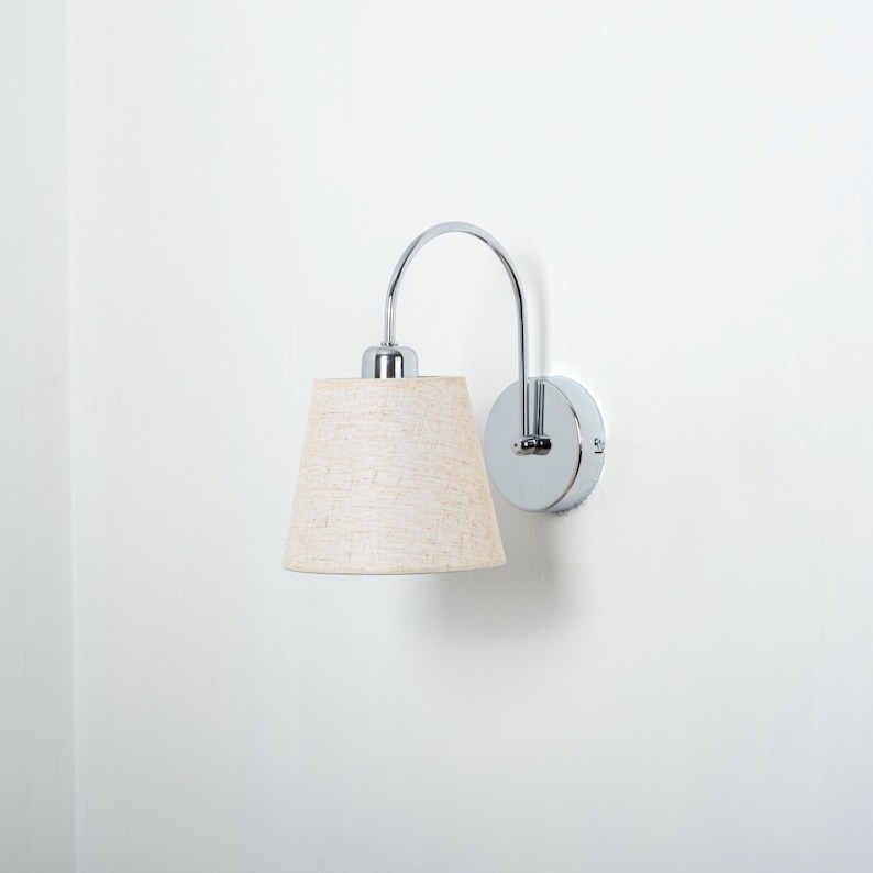 May include: A chrome wall sconce with a curved arm and a beige fabric lampshade.