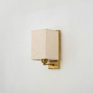 May include: A brass wall sconce with a square, off-white fabric shade.