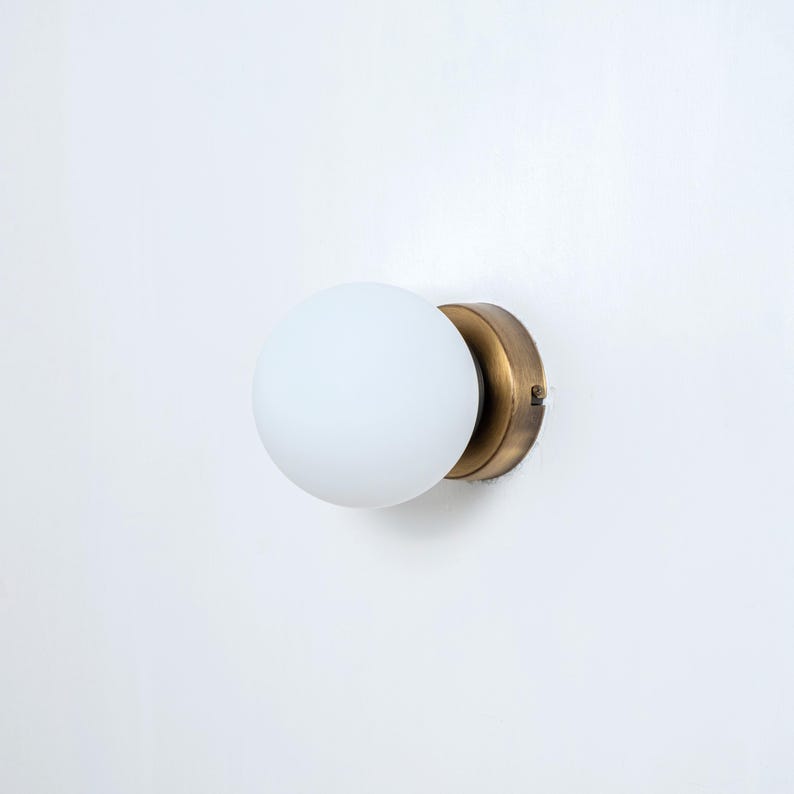 May include: A brass wall sconce with a white frosted glass globe.
