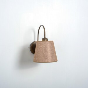 May include: A wall-mounted light fixture with a curved arm and a beige fabric lampshade.