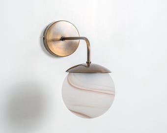 Wandlamp met marmeren glazen bol en verouderde messing afwerking.