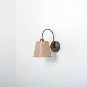 May include: A wall-mounted light fixture with a curved arm and a beige fabric lampshade.