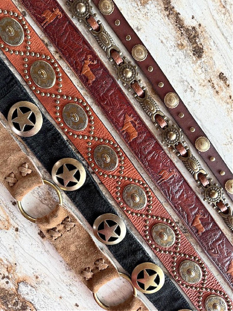 Peut inclure: Cinq ceintures en cuir diff&eacute;rentes avec divers ornements m&eacute;talliques. Les ceintures pr&eacute;sentent diff&eacute;rents motifs, notamment des &eacute;toiles, des cercles et des motifs animaliers. Les ceintures sont toutes brunes et ont un style rustique et western.