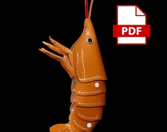 May include: A handcrafted, orange leather shrimp keychain with white stitching and a red antenna. The shrimp has segmented body sections and detailed claws. The PDF icon is in the upper right corner.