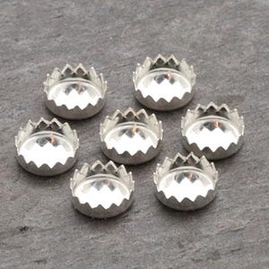 May include: Seven silver-toned metal settings for jewelry making. Each setting has a scalloped edge and a round center.