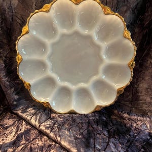 May include: White ceramic serving dish with a scalloped edge and gold trim. The dish has 12 individual compartments around a central well. The gold trim adds a touch of elegance to this serving piece.