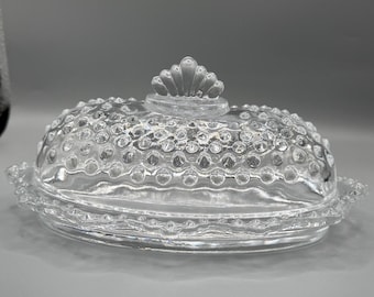Mantequera Rave Vintage L.E. Smith de cristal transparente con forma de tachuela. Firma con la letra S en cursiva.