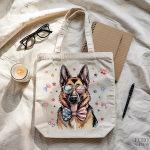 May include: A cream tote bag with a German Shepherd illustration wearing sunglasses with an American flag design and a patriotic bow tie. The bag is decorated with stars and bow tie graphics. The text "ECHO SIP CO." is visible.