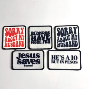 May include: A collection of five square patches with black borders and white backgrounds. The patches feature various phrases in bold, stylized fonts, including "SORRY ABOUT MY HUSBAND," "BLONDES HAVE MORE FUN," "JESUS saves I spend," and "HE'S A 10 BUT IN PESOS."