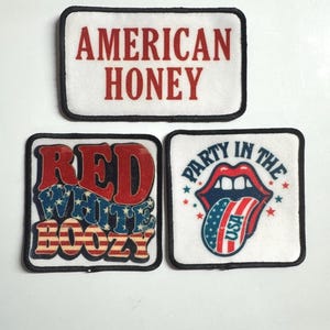 May include: Three rectangular patches with black borders. The top patch reads "AMERICAN HONEY" in red. The second patch says "RED WHITE BOOZY" with a red, white, and blue design. The third patch says "PARTY IN THE USA" with a red lip design.