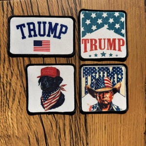 May include: Four rectangular patches with black borders. One patch has the word "TRUMP" above an American flag. Another has "TRUMP" over a blue star pattern. A third shows a black dog with a red hat and bandana. The last patch features a man in a cowboy hat.