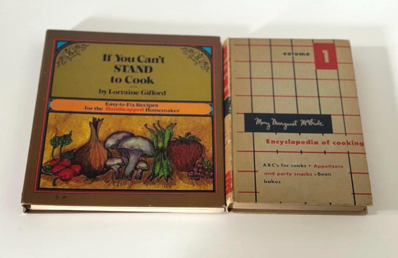May include: Two vintage cookbooks are displayed side-by-side. The first, "If You Can't Stand to Cook," features a colorful illustration of vegetables. The second, "Encyclopedia of Cooking," is volume 1 with a grid design.