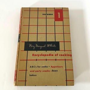 May include: A vintage cookbook titled "Encyclopedia of Cooking" by Mary Margaret McBride. The cover is tan with a red and black grid pattern. The book is labeled "Volume 1" in a red box. The book's contents include ABC's for cooks, appetizers, and bean bakes.