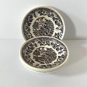May include: Three white ceramic dessert bowls with a black and brown floral pattern and a cottage scene in the center.