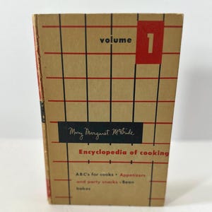 May include: A vintage cookbook titled "Encyclopedia of Cooking" by Mary Margaret McBride. The cover is tan with a red and black grid pattern, the word "volume" and the number "1" in a red box. The book's title and author are also visible.