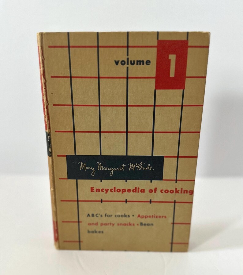 May include: A vintage cookbook titled "Encyclopedia of Cooking" by Mary Margaret McBride. The cover is tan with a red and black grid pattern, the word "volume" and the number "1" in a red box. The book's title and author are also visible.
