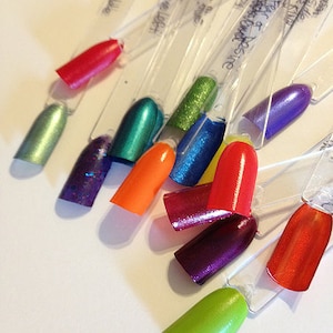 May include: A set of ten nail polish colors displayed on clear plastic sticks. The colors include green, red, orange, blue, purple, and gold. The colors are arranged in a rainbow pattern.