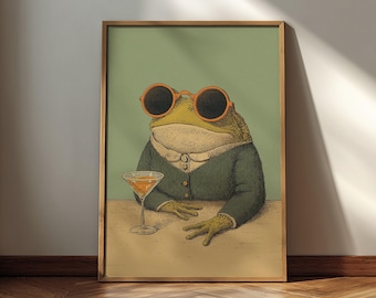 May include: A framed print featuring a dapper frog wearing orange sunglasses and a suit, holding a cocktail. The frog is depicted with human-like features, seated at a table. The background is a muted green, and the overall style is vintage.