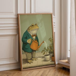 May include: A framed art print featuring a dapper frog in a teal blazer and bow tie, watering plants with an orange watering can. The illustration has a vintage aesthetic, with a light green background and a wooden frame.