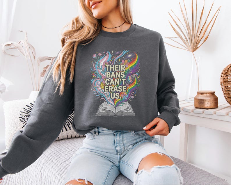 A woman wearing a gray sweatshirt with a colorful graphic design on it, sitting on a couch.