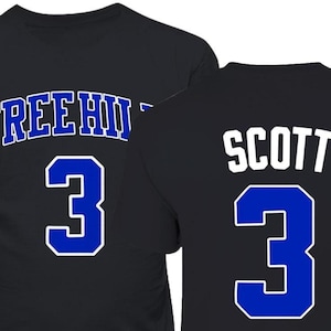 May include: Black t-shirt with blue and white lettering. The front of the shirt says "TREE HILL" and has the number "3" in blue. The back of the shirt says "SCOTT" and has the number "3" in blue.