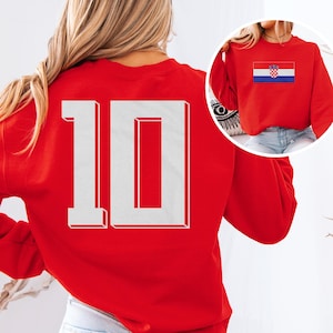 A woman wearing a red sweater with the number 10 on it, and a small image of the Croatia national flag on the back of the sweater.