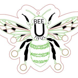 May include: A white, bee-shaped design with the words "BEE U TIFUL" in black. The bee has green and black details, with a red outline. The design includes circles around the edges, and is suitable for crafting or decoration.