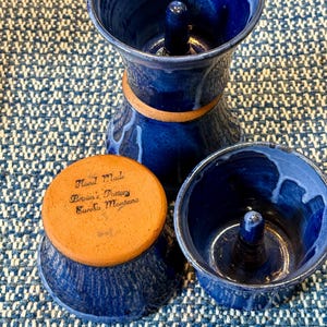 May include: Two blue ceramic cake rings with a center ring. The bottom ring has a brown base with the text "Hand Made Brown's Pottery Eureka Montana".