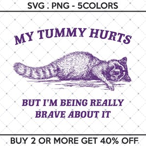 Op de afbeelding: Een paarse illustratie van een wasbeer die op zijn zij ligt met de tekst "MY TUMMY HURTS BUT I'M BEING REALLY BRAVE ABOUT IT" en "BUY 2 OR MORE GET 40% OFF".