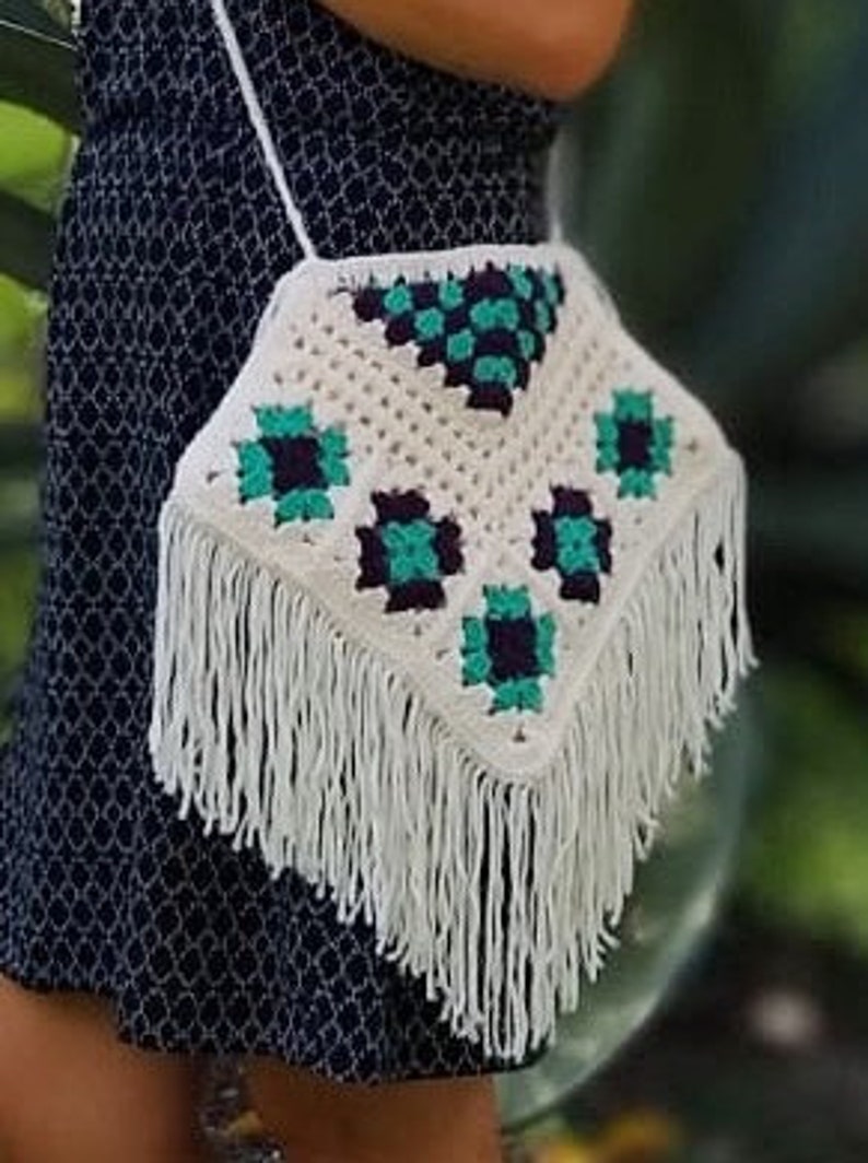 May include: White crocheted bag with a geometric pattern in teal and purple. The bag has a fringe border and a white strap.