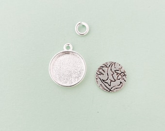 Könnte beinhalten: Drei silberfarbene Metall-Schmuckstücke: ein runder Anhänger mit glatter Oberfläche, ein runder Anhänger mit strukturiertem Design und ein Sprungring.