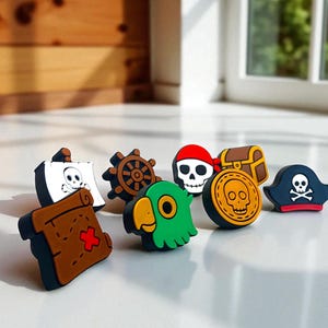 May include: A selection of pirate-themed charms in various colours. The charms depict a treasure map, ship's wheel, skull with a red bandana, treasure chest, gold coin with a skull, parrot, and a pirate hat with a skull and crossbones.