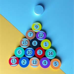 Puede incluir: Una colorida disposición de bolas de billar, numeradas del 1 al 15, dispuestas en un triángulo. Las bolas son de varios colores, incluyendo amarillo, verde, rojo y morado, sobre un fondo azul y amarillo. Un círculo blanco en la parte superior.