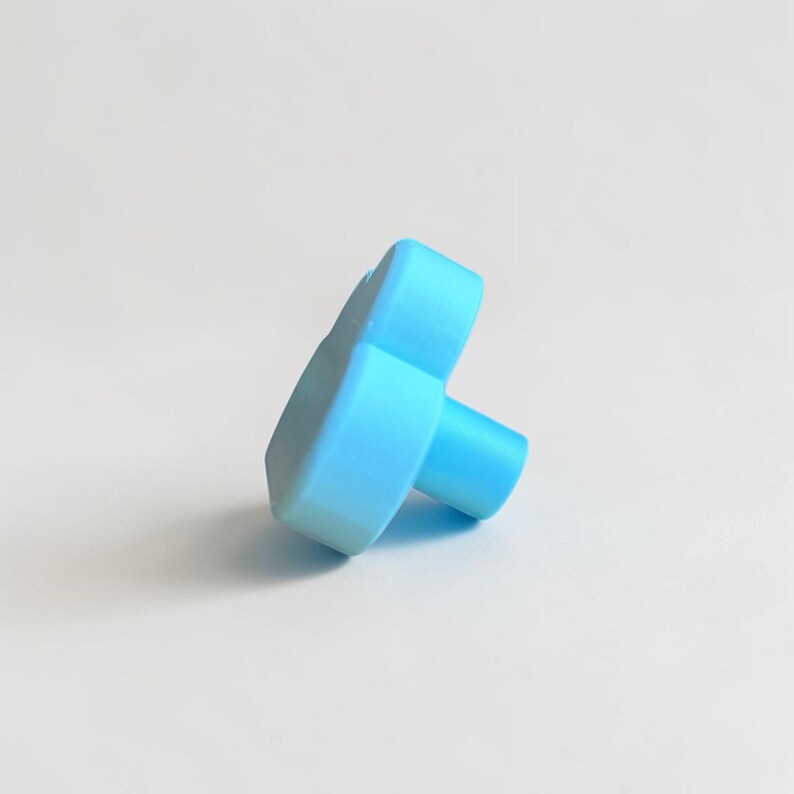 May include: A light blue cabinet knob shaped like a cloud. The knob features a smooth, matte finish with a rounded, puffy silhouette and a cylindrical base extending from the back, designed for attachment to furniture or cabinetry doors.