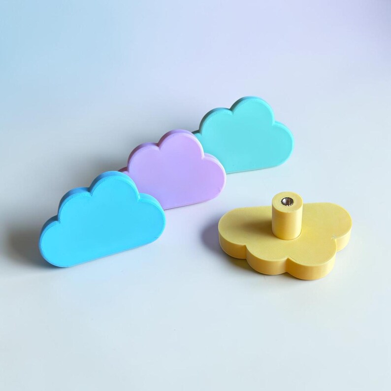 May include: Four cloud-shaped drawer knobs in pastel colors including bright blue, light purple, teal, and yellow. Each knob features a smooth, matte finish and a central cylindrical mounting post with a metal-lined screw hole on the back side.